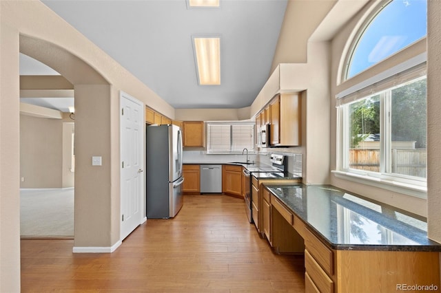 8985 Edgewood Ln, Highlands Ranch, CO 80130 - kitchen featuring appliances with stainless steel finishes, light wood finished floors, a sink, and arched walkways