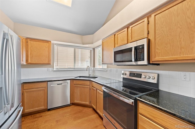 8985 Edgewood Ln, Highlands Ranch, CO 80130 - kitchen featuring stainless steel appliances, a sink, vaulted ceiling, tasteful backsplash, and light wood finished floors