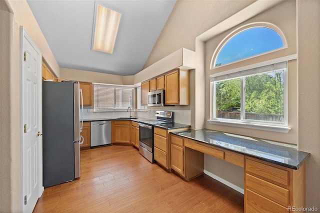 8985 Edgewood Ln, Highlands Ranch, CO 80130 - kitchen featuring appliances with stainless steel finishes, a sink, light wood-style flooring, a desk, and high vaulted ceiling