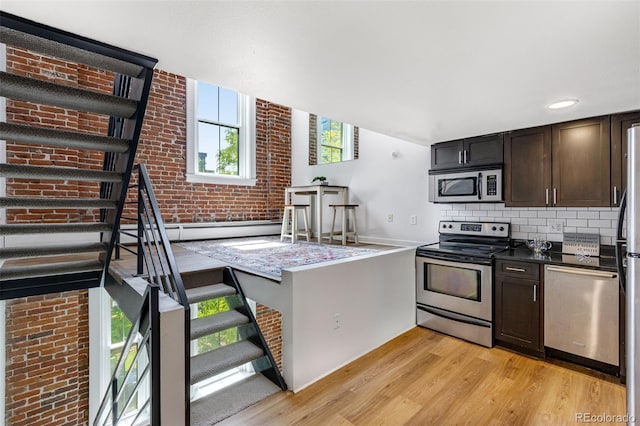 2193 Arapahoe St Unit 15, Denver, CO 80205 - kitchen with appliances with stainless steel finishes, light wood-style flooring, dark brown cabinetry, decorative backsplash, and dark countertops
