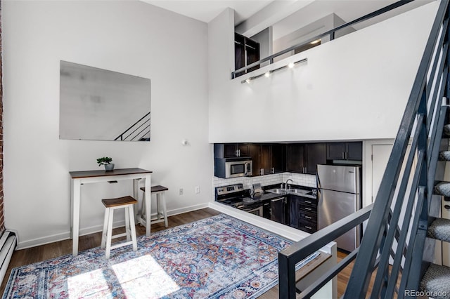 2193 Arapahoe St Unit 15, Denver, CO 80205 - kitchen featuring stainless steel appliances, a sink, wood finished floors, decorative backsplash, and a baseboard heating unit