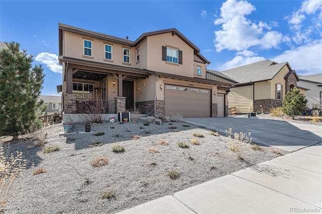 view of front of property featuring stucco siding, covered porch, a garage, stone siding, and driveway