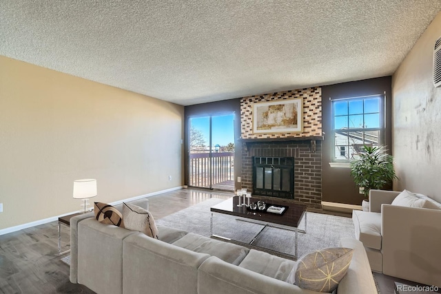 living area featuring a textured ceiling, a brick fireplace, wood finished floors, and baseboards