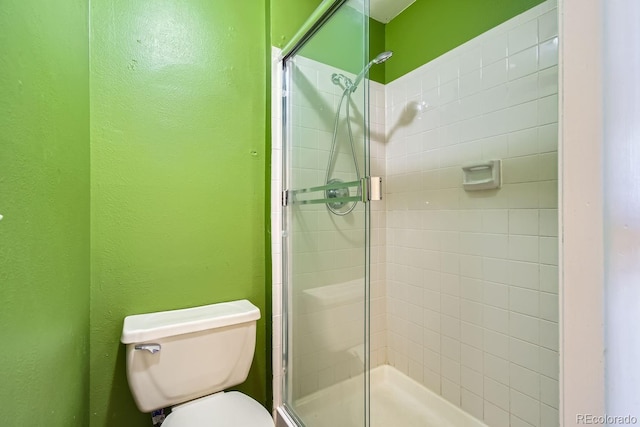 bathroom featuring a stall shower, toilet, and a textured wall