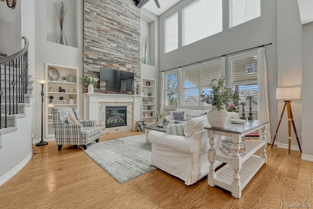 26566 E Peakview Dr, Aurora, CO 80016 - living area with a fireplace, baseboards, wood finished floors, a towering ceiling, and stairway