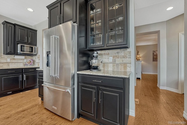 26566 E Peakview Dr, Aurora, CO 80016 - kitchen with light wood-style floors, decorative backsplash, baseboards, and appliances with stainless steel finishes