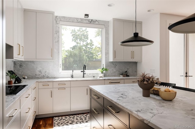 3130 Wyandot St, Denver, CO 80211 - kitchen featuring a sink, black electric cooktop, light stone countertops, decorative backsplash, and decorative light fixtures