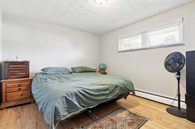 3691 Allison St, Wheat Ridge, CO 80033 - bedroom with a baseboard heating unit, wood finished floors, and baseboards