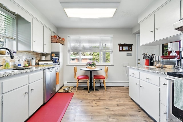 3691 Allison St, Wheat Ridge, CO 80033 - kitchen featuring appliances with stainless steel finishes, a sink, white cabinetry, light wood-style floors, and tasteful backsplash