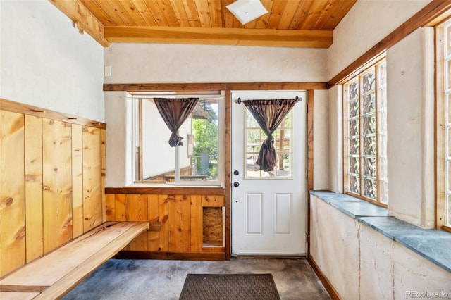 doorway to outside featuring beamed ceiling, wooden ceiling, wooden walls, and concrete flooring