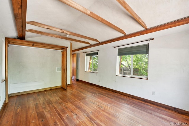 unfurnished room featuring vaulted ceiling with beams, visible vents, hardwood / wood-style flooring, and baseboards