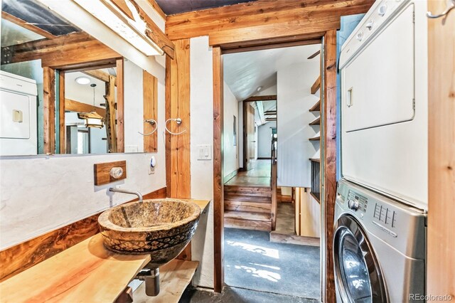 laundry room featuring stacked washer and dryer and a sink