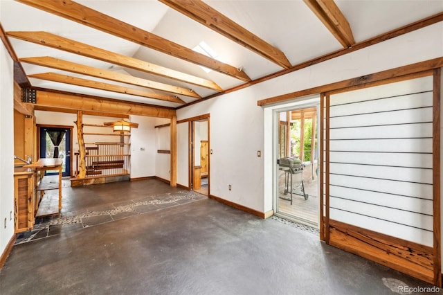 interior space with beamed ceiling, concrete floors, and baseboards