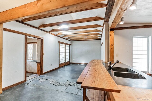 kitchen featuring vaulted ceiling with beams, sink, a wealth of natural light, and wooden counters