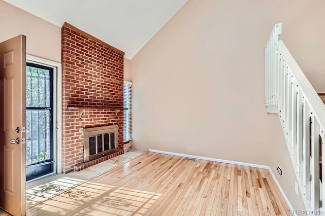 unfurnished living room with lofted ceiling, a fireplace, and light hardwood / wood-style floors