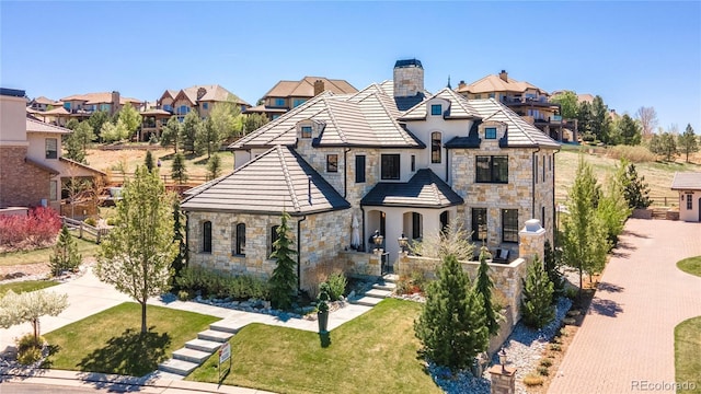 tudor house with a residential view, a chimney, stone siding, and stucco siding
