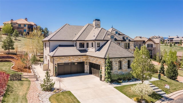 view of front of house with driveway, a chimney, fence, stone siding, and stucco siding