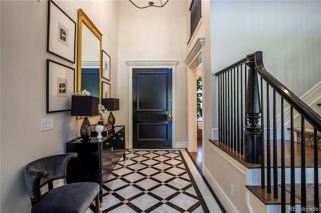 foyer with stairway, baseboards, and a towering ceiling