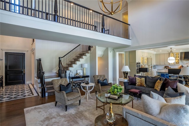 living area featuring crown molding, stairs, wood finished floors, baseboards, and a high ceiling