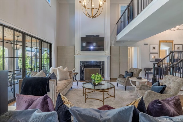 living area with plenty of natural light, stairs, a high ceiling, and a chandelier