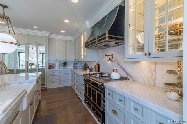 kitchen with crown molding, light stone countertops, tasteful backsplash, custom exhaust hood, and glass insert cabinets