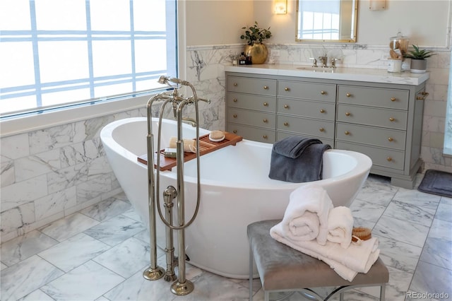 bathroom featuring a freestanding tub, tile walls, a wainscoted wall, vanity, and marble finish floor