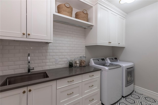 washroom featuring cabinet space, a sink, baseboards, tile patterned floors, and separate washer and dryer