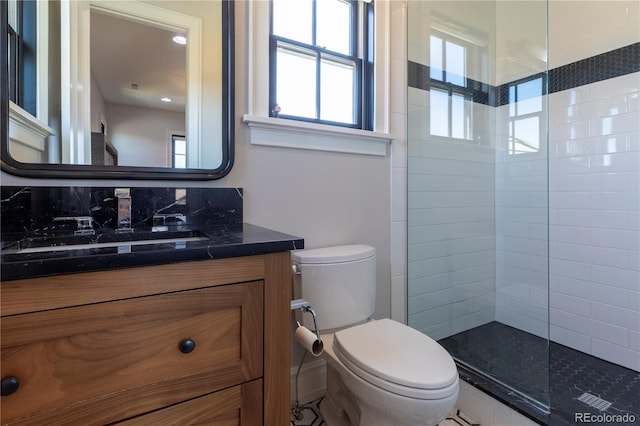 bathroom with vanity, toilet, and tiled shower