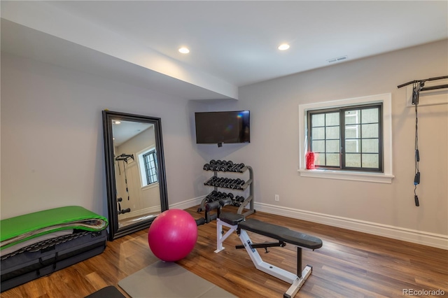 exercise room featuring baseboards, recessed lighting, wood finished floors, and visible vents