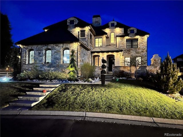 french country home with a chimney and stone siding