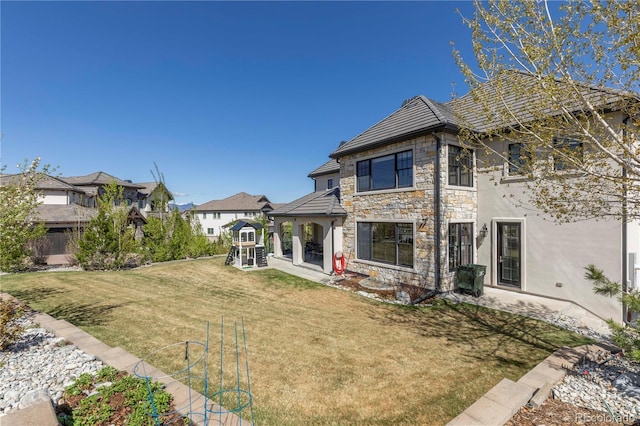 back of house with a patio, stucco siding, a yard, and stone siding
