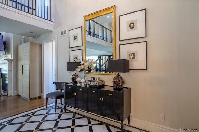 interior space featuring baseboards, visible vents, and a towering ceiling