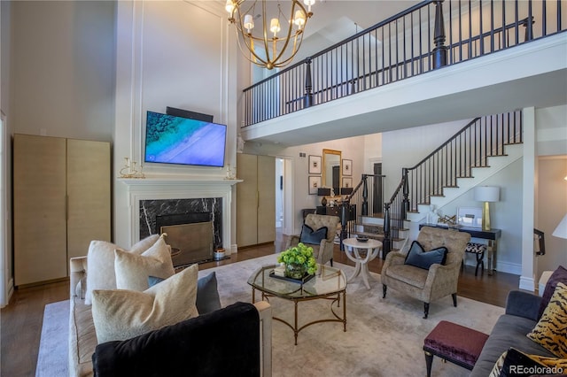 living room featuring a chandelier, wood finished floors, stairway, and a towering ceiling