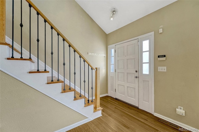 foyer entrance featuring light wood-type flooring, vaulted ceiling, stairway, and baseboards