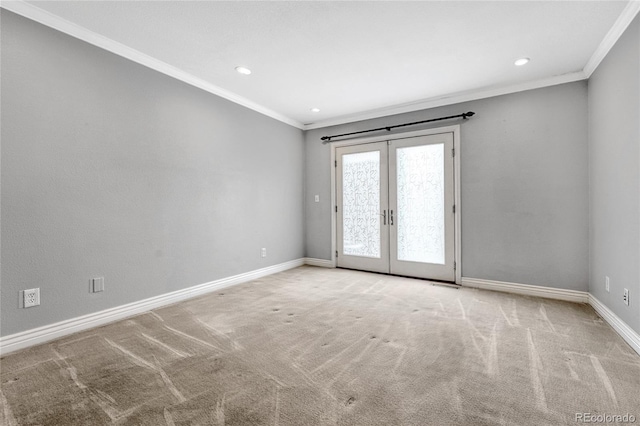 spare room featuring french doors, light colored carpet, crown molding, and baseboards