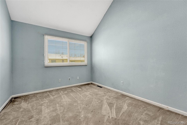 unfurnished room with light carpet, lofted ceiling, visible vents, and baseboards