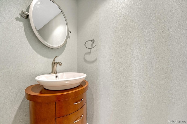 bathroom with a textured wall and vanity