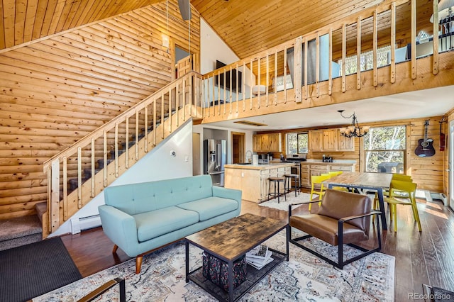 living area with high vaulted ceiling, hardwood / wood-style flooring, rustic walls, stairway, and an inviting chandelier