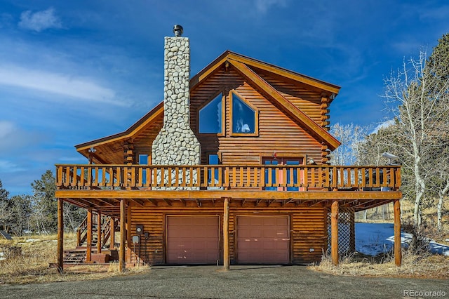 view of front of house featuring stairway, log exterior, a chimney, a garage, and driveway