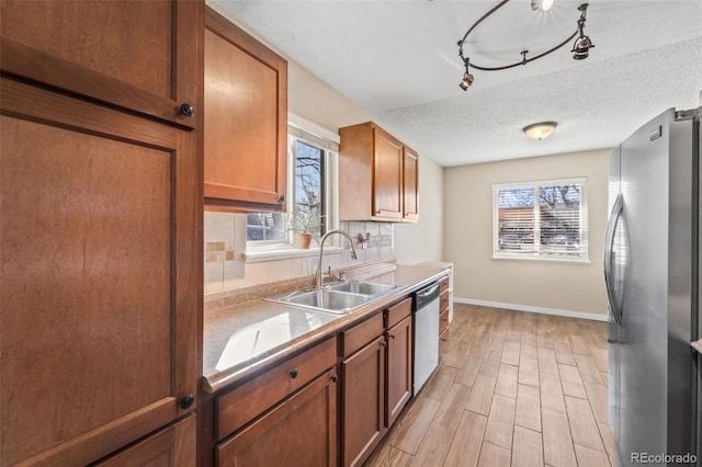 1940 Carmel Dr, Colorado Springs, CO 80910 - kitchen featuring light wood-style floors, a sink, stainless steel appliances, decorative backsplash, and baseboards