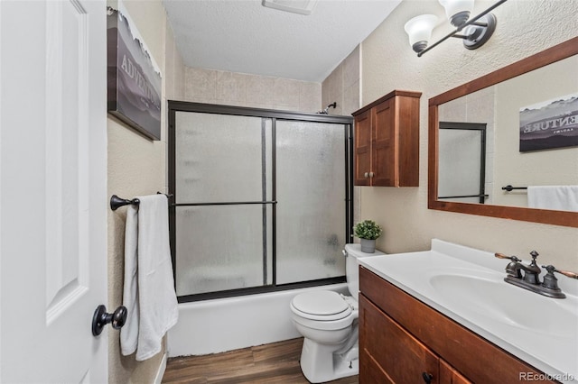 1940 Carmel Dr, Colorado Springs, CO 80910 - full bathroom with vanity, enclosed tub / shower combo, a textured ceiling, toilet, and wood finished floors