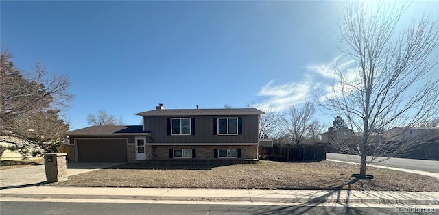 tri-level home featuring fence, board and batten siding, concrete driveway, a garage, and brick siding