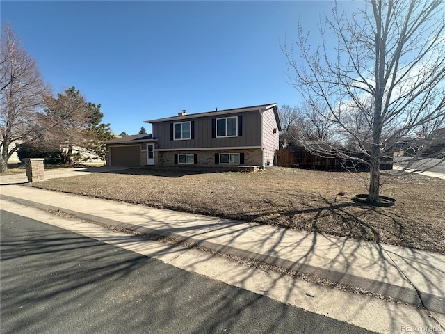 split level home featuring brick siding, an attached garage, and concrete driveway