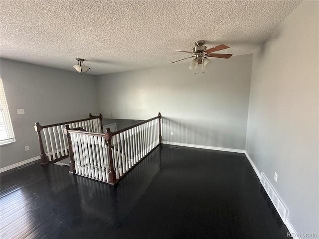 interior space featuring visible vents, a textured ceiling, baseboards, and wood finished floors