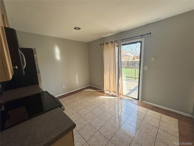 kitchen with dark countertops, visible vents, baseboards, light tile patterned floors, and range with electric stovetop