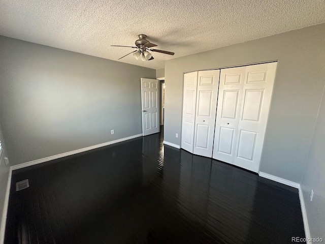 unfurnished bedroom featuring a closet, a textured ceiling, baseboards, and dark wood-style flooring