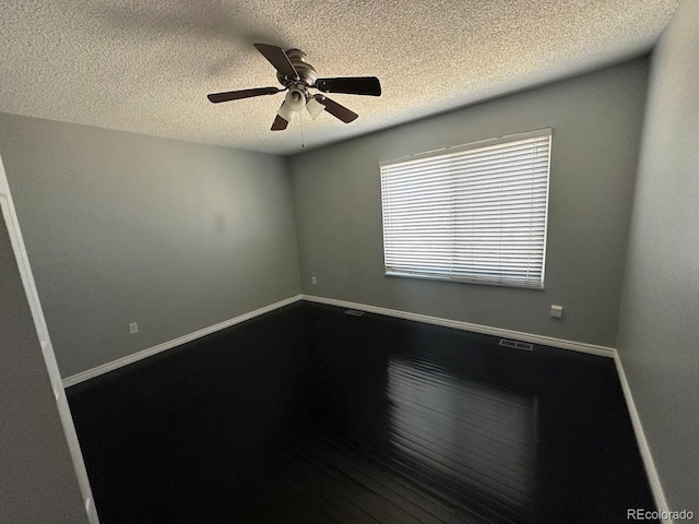 unfurnished room featuring ceiling fan, dark wood-type flooring, baseboards, and a textured ceiling