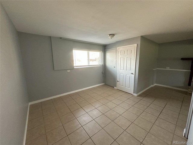 unfurnished bedroom with a closet, baseboards, and light tile patterned flooring