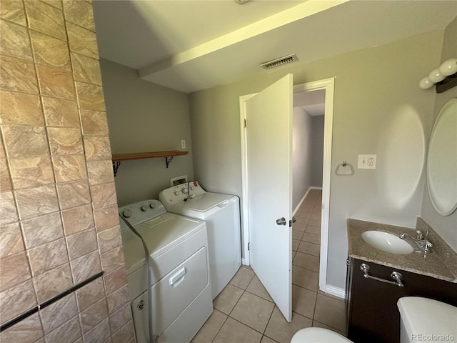 washroom featuring visible vents, washer and clothes dryer, light tile patterned floors, laundry area, and a sink