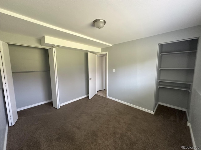 unfurnished bedroom featuring dark carpet and baseboards